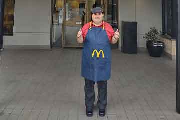 Man wearing McDonalds uniform giving thumbs up out the front of the store.