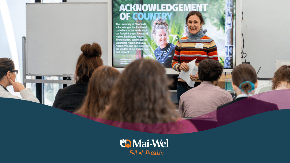 Woman presenting to youth at pathways to employment day with an acknowledgement of country on a screen behind her.