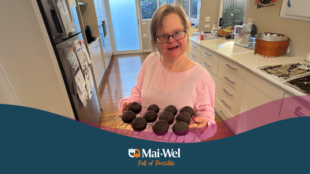 Woman in a kitchen holding chocolate muffins which she baked while building life skills