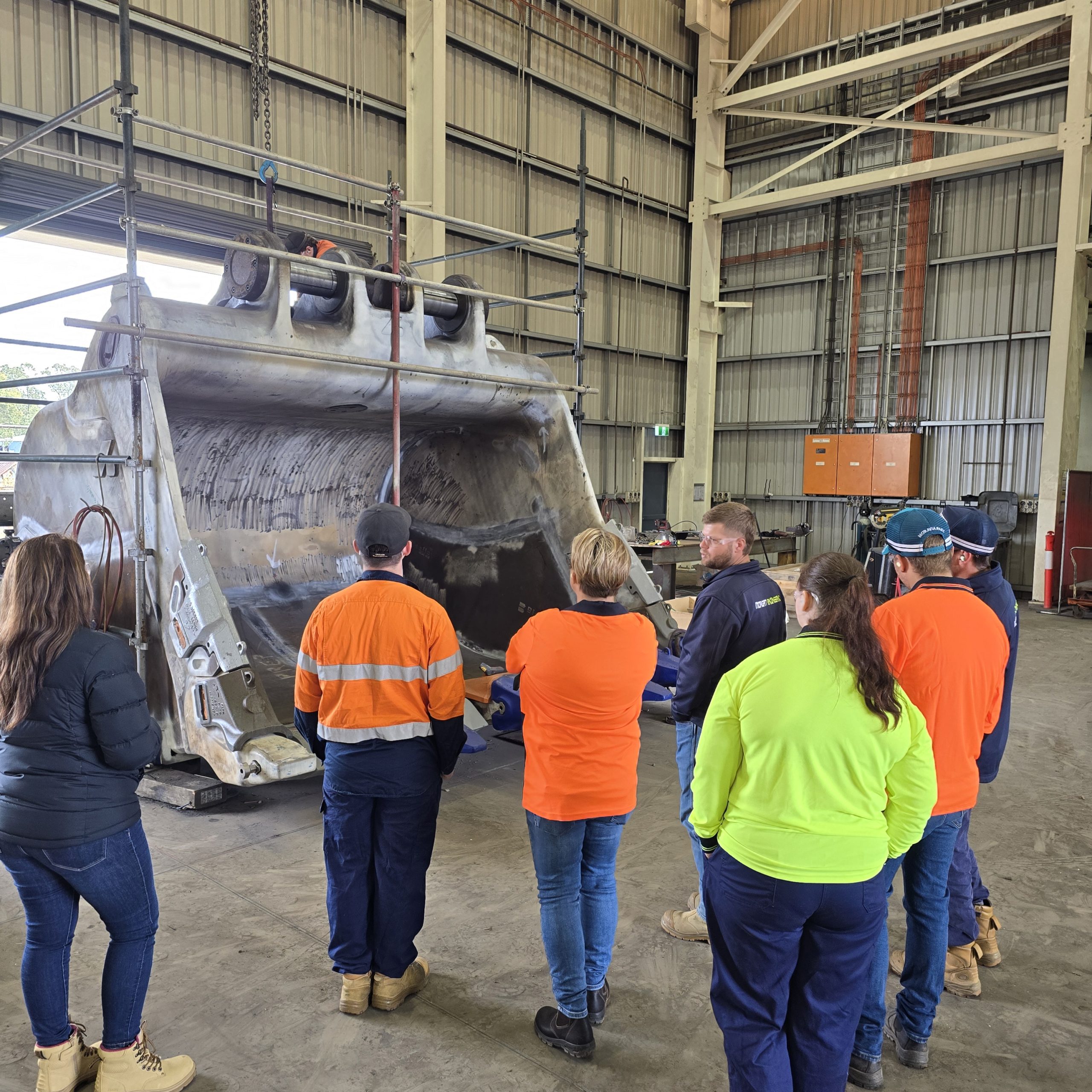 Group of Transition to Work Participants and Morgan Engineering employees looking at a large loader bucket.