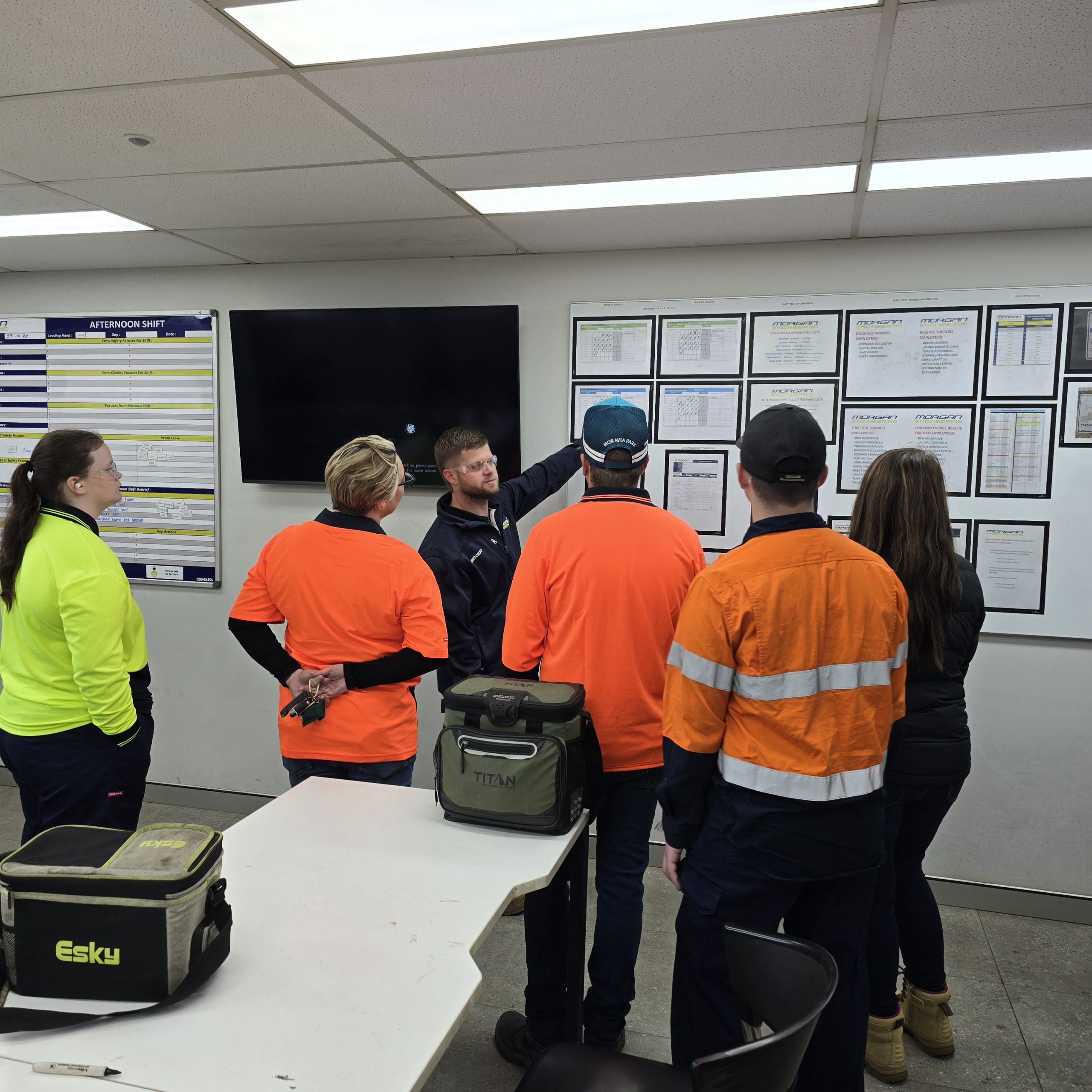 Group of Transition to Work Participants and Morgan Engineering employees looking at a notice board in an office.