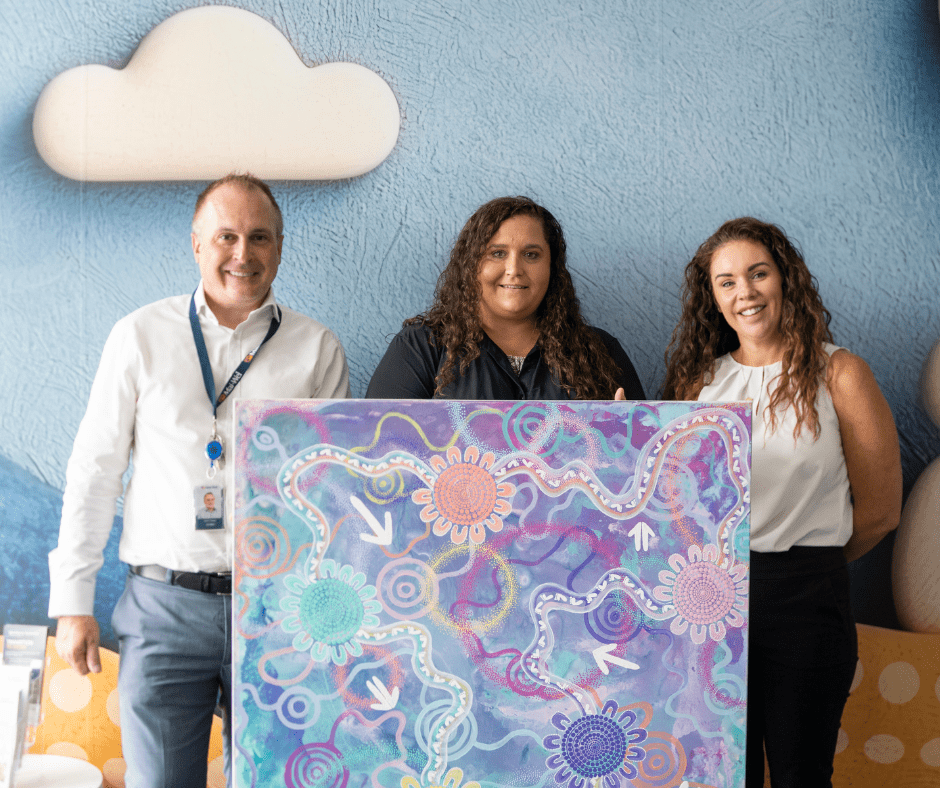 Build Presentation 2 CEO john Cleary and Business Development and Partnerships Specialist holding the "Build" artwork alongside artist Jess Sulter during a presentation.