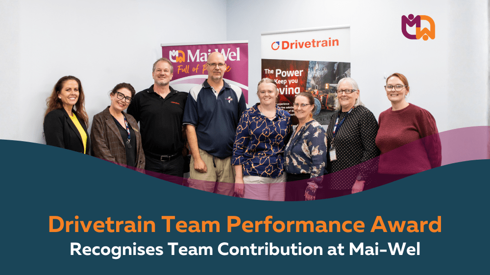 A group of seven stand together in front of Mai-Wel and Drivetrain pull-up banners, marking the Drivetrain Team Performance Award. Text overlay reads "Drivetrain Team Performance Award Recognises Team Contribution at Mai-Wel."